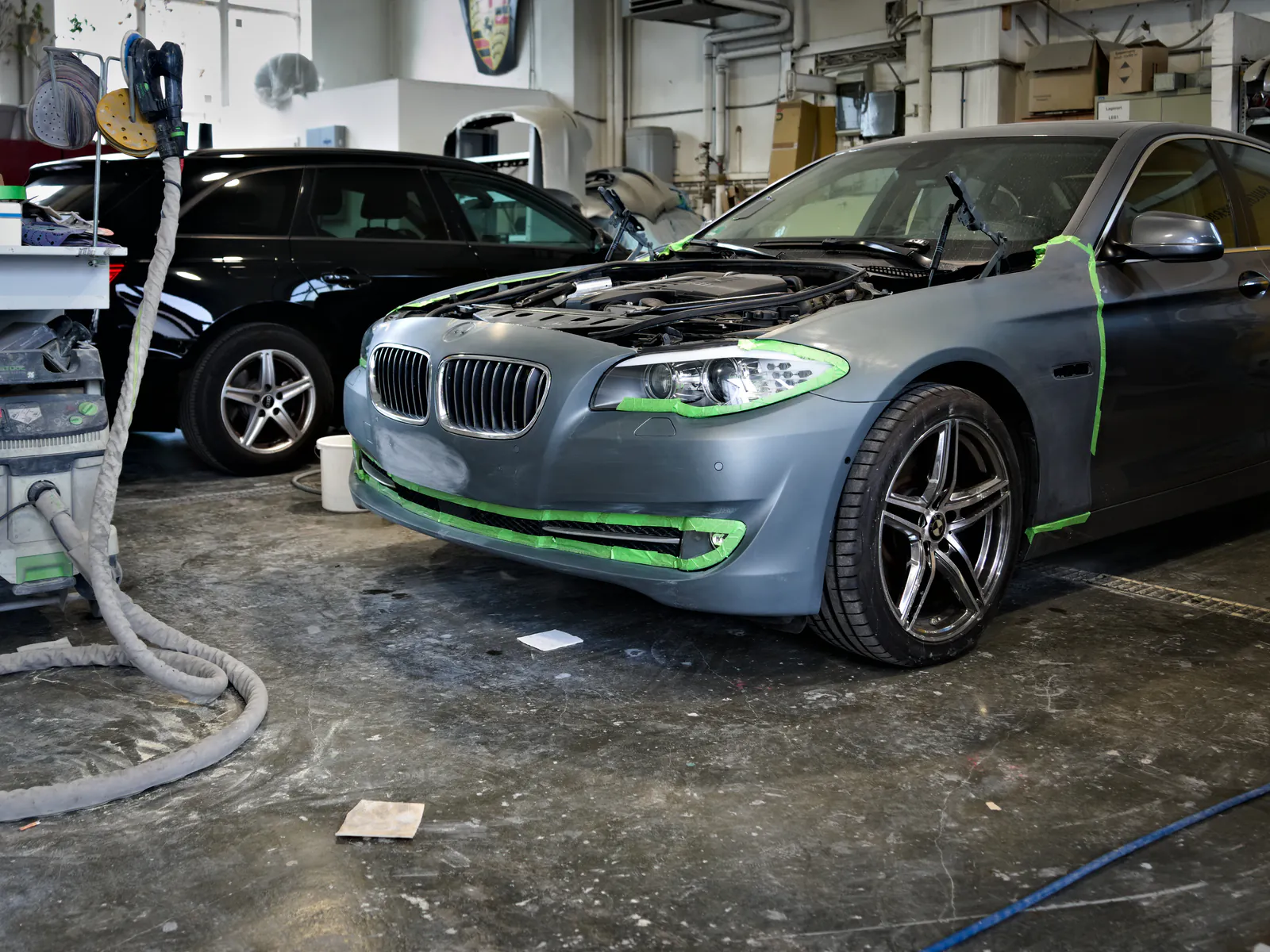 BMW in der Fahrzeugvorbereitung: Haube demontiert und Kanten abgeklebt